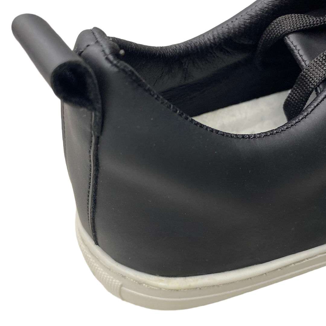 Close-up of a black shoe with a white sole on a white background